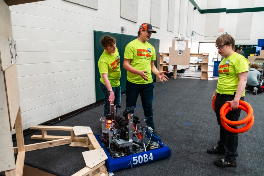 three man standing next to robot